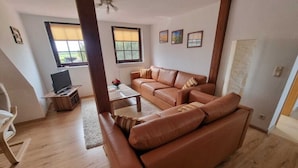 A living room with a brown leather sofa, a wooden coffee table, and a television on a stand. - Kinderparadies - Ferienwohnung mit Garten (Blowatz)