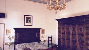 A bedroom with a wooden bed, a chandelier, a large wooden wardrobe, and framed artwork on the wall. - Venice Region Castle With Garden Views (Romano d'Ezzelino)