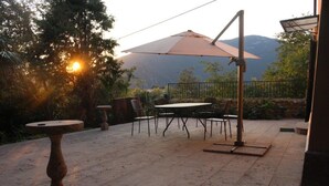 An outdoor patio with a table and chairs, a large umbrella, and a stone table. - Venice Region Castle With Garden Views (Romano d'Ezzelino)