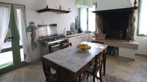 A kitchen with a gas stove, a hanging light fixture, and a fireplace. - Venice Region Castle With Garden Views (Romano d'Ezzelino)