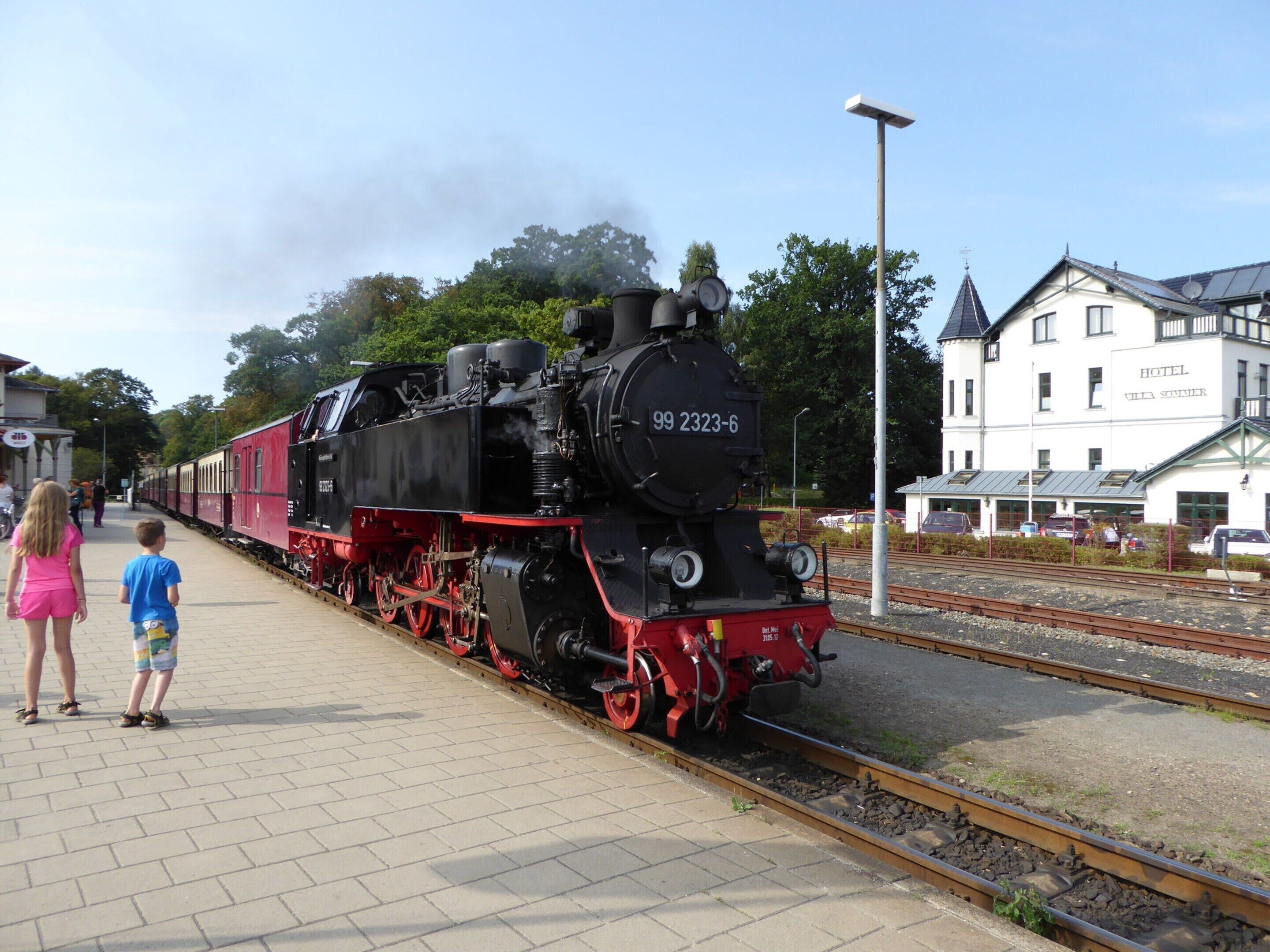 Een zwarte stoomlocomotief met het nummer 99 2323-6 op een treinstation.
