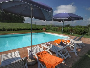 A poolside area with lounge chairs and umbrellas, surrounded by a landscaped garden. - Farmhouse in Proceno With Pool (Proceno)