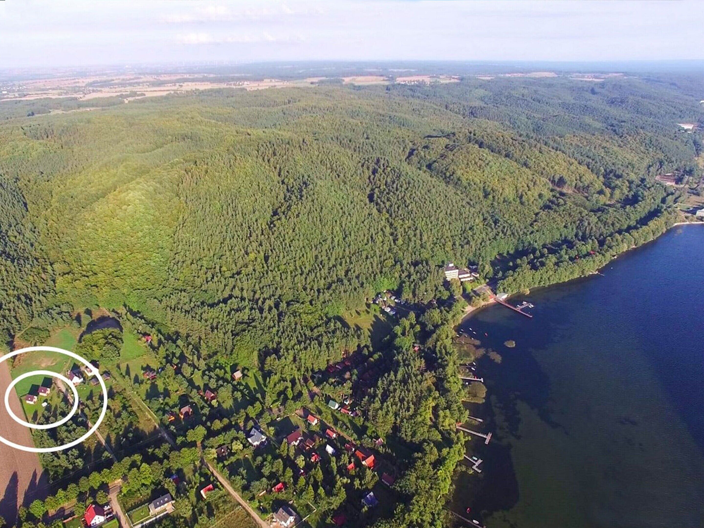 Ett flygbildsbild av ett skogsområde med en liten grupp byggnader nära en sjö.