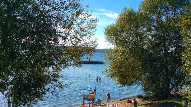 A beach with a lifeguard station, people swimming, and a clear view of the water.
