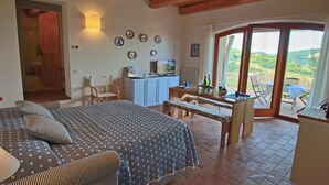 A bedroom with a bed, a desk, and a view of the outdoors. - Tranquil Hilltop Cottage (Montelabbate)