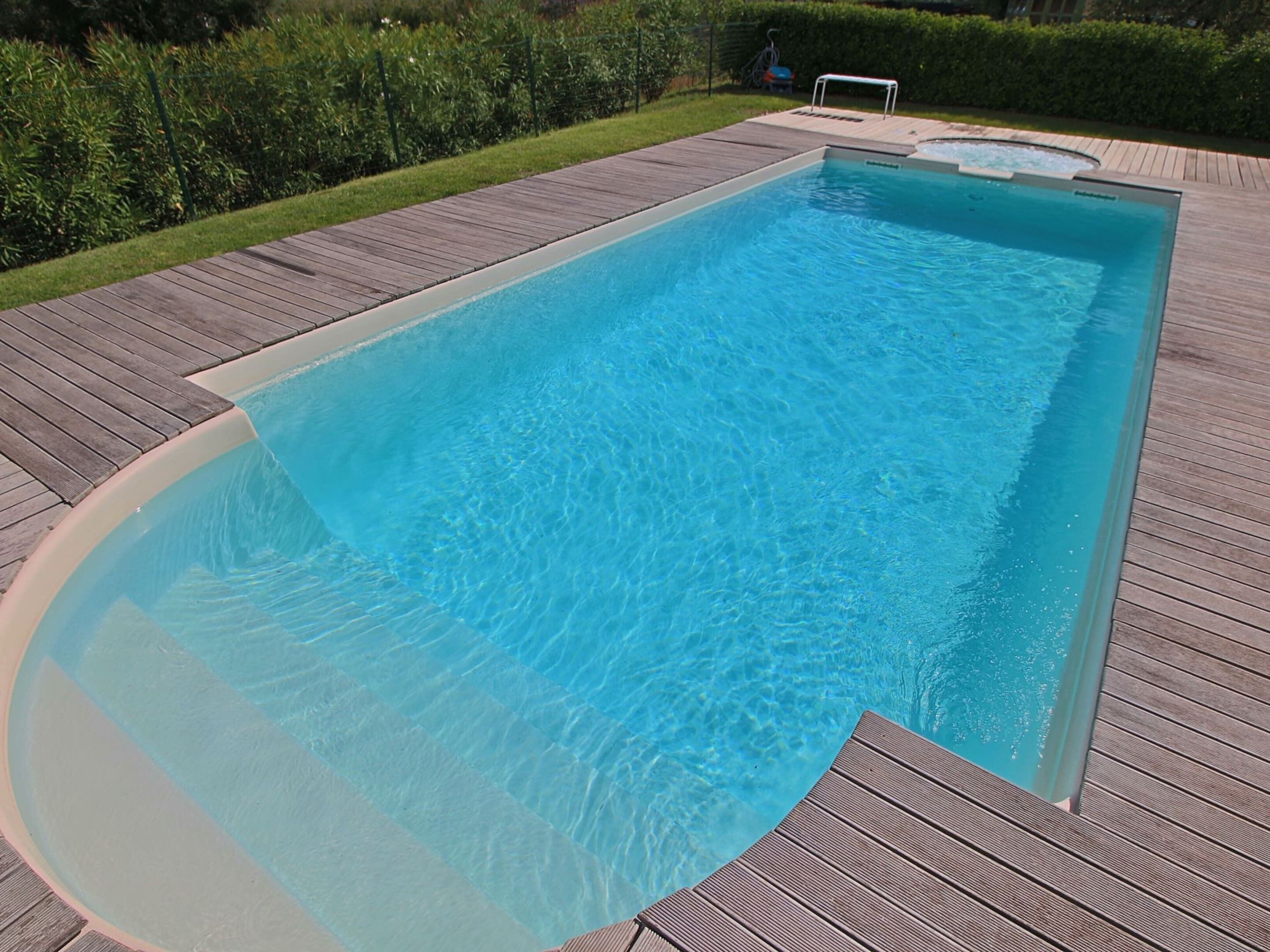 Una piscina rectangular con un deck de madera alrededor.