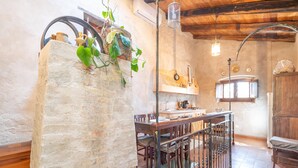 A rustic kitchen with a stone wall, wooden beams, and a hanging light fixture. - Holiday Home in Stilo With Pool & Views (Stilo)