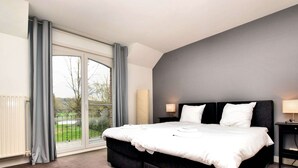 Een moderne hotelkamer met een groot bed, uitzicht door een schuifdeur en een donkergrijze accentmuur.