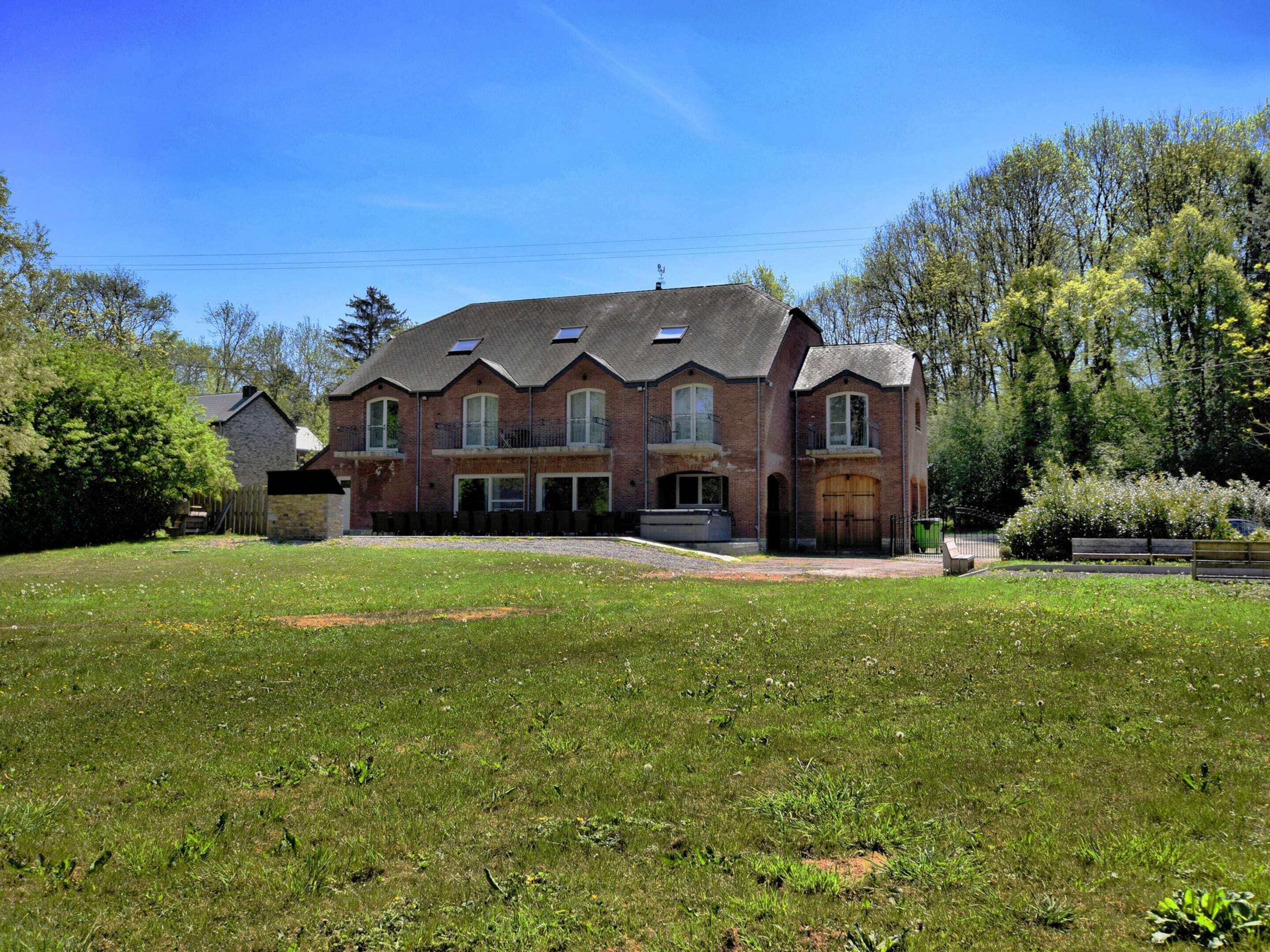 En stor murstensvilla med en symmetrisk facade, mange vinduer og en veranda.