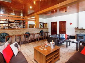 Un vaste espace de vie comprenant un bar en bois, des canapés en cuir et une cheminée.