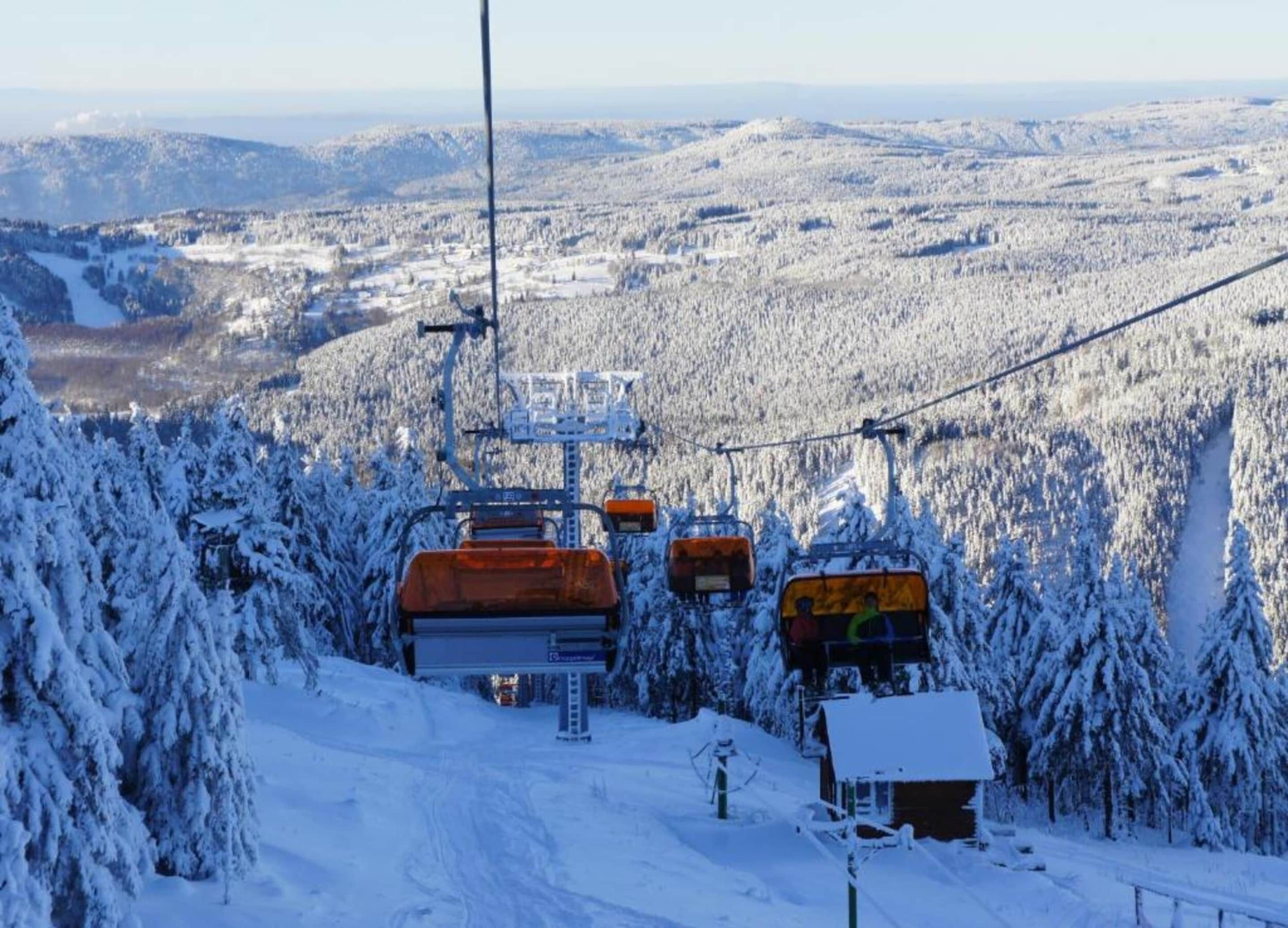 A ski lift with cabins moving up a snowy mountain slope.