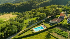 A residential area with a swimming pool, surrounded by lush greenery and hills. - Belvilla by OYO Gallorimpi (Dicomano)