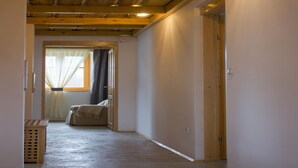 A narrow hallway with wooden beams on the ceiling, a door on the right, and a window with curtains at the end. - Comfy Holiday Home in Bunjevci With Hot Tub (Vrbovsko)