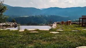 A serene outdoor setting with a clear view of distant mountains, a small pond, and a wooden bench. - Comfy Holiday Home in Bunjevci With Hot Tub (Vrbovsko)