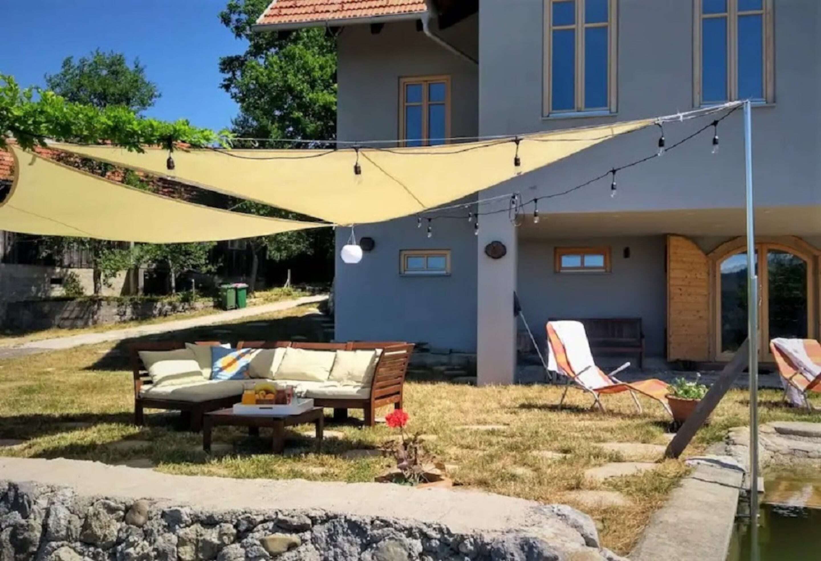 A house with a patio area featuring a sofa, lounge chairs, and a string of lights.