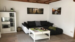 A living room with a sofa, a coffee table, a bookshelf, and two framed pictures on the wall. - Ferienhaus in Neu Poserin for 5 Personen (Neu Poserin)
