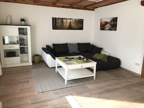 A living room with a sofa, a coffee table, a bookshelf, and two framed pictures on the wall.