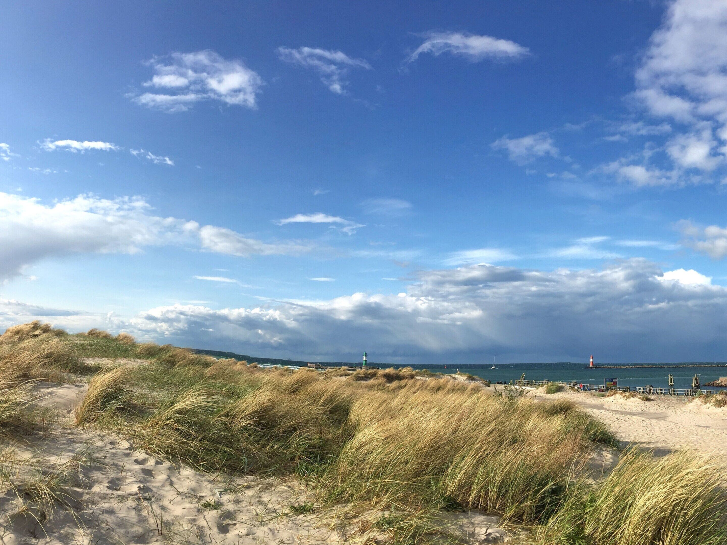 A beach with sand dunes and a lighthouse in the distance.