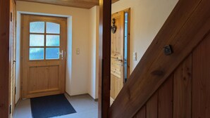 A wooden interior hallway with a wooden door and a light fixture on the ceiling.