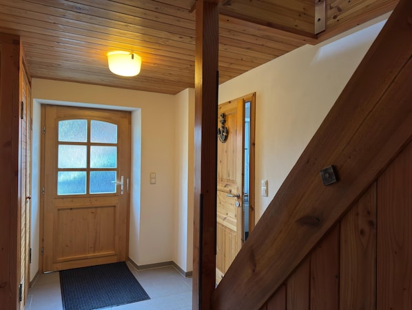 A wooden interior hallway with a wooden door and a light fixture on the ceiling.