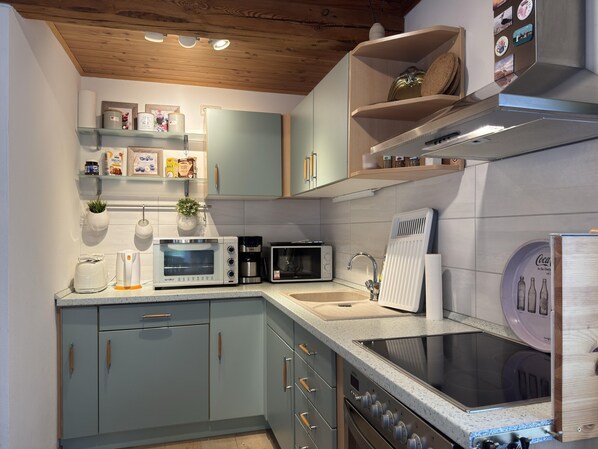 A modern kitchen with a built-in oven, microwave, coffee maker, and a sink.