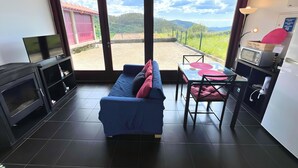 Een gezellige woonkamer met een blauwe bank, een televisie en een eethoek met een tafel en stoelen.