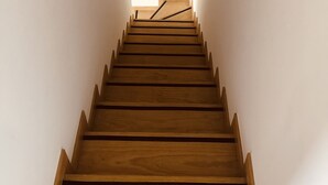 Een houten trap met een leuning, die uitkomt op een plateau met een lamp.