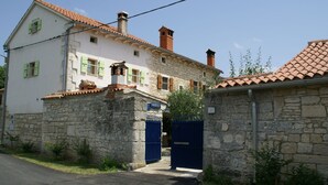 A two-story stone building with a tiled roof, a blue gate, and a sign reading "MARIO". - Stone Holiday Home in Peresiji With Pool (Svetvincenat)