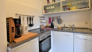 Eine kleine Küche mit Geschirrspüler, Backofen und Kaffeemaschine auf der Arbeitsfläche.