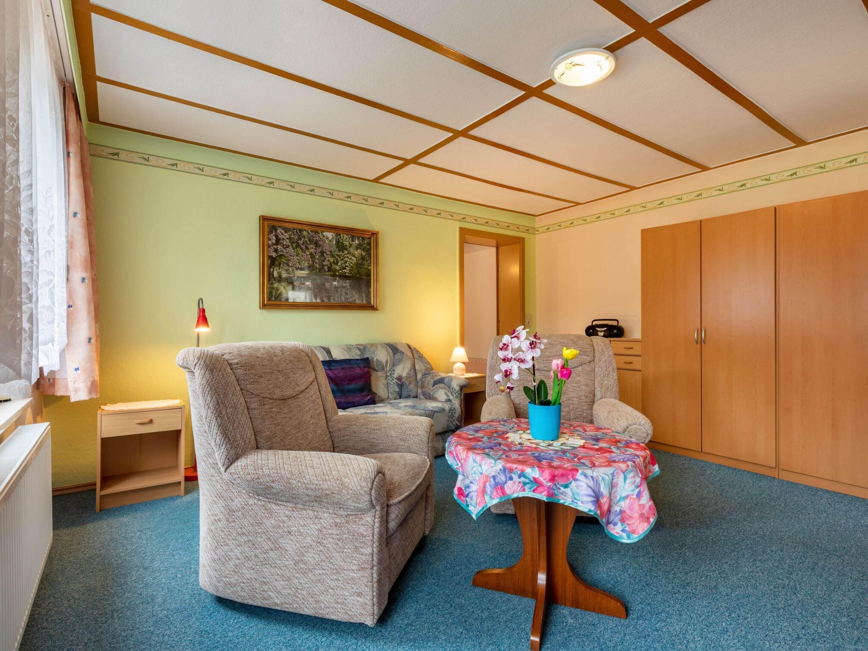 A cozy room with a sofa, a small table with a floral tablecloth, and a cabinet.