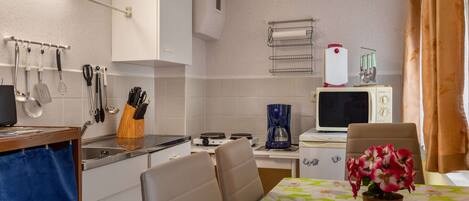 A compact kitchen with a stove, microwave, and a small dining area with a table and chairs.