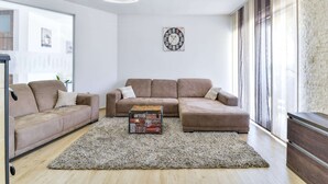 A modern living room with a sectional sofa, a small wooden chest, and a decorative wall clock. - Modern Home in Quiet Pristeg (Benkovac)
