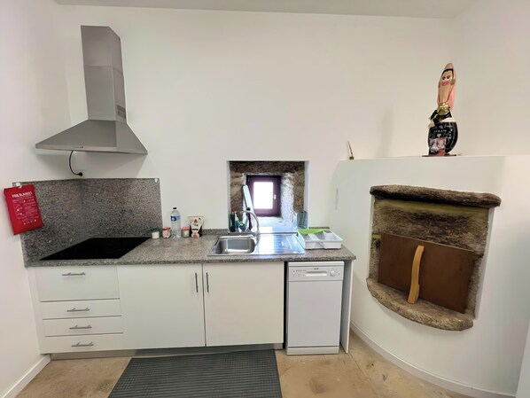 A compact kitchen with a built-in stove, a dishwasher, and a stone backsplash. - Ponte de Lima Rural Refuge (Ponte de Lima)