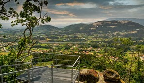 A scenic overlook with a metal railing, a rocky outcrop, and a view of a valley with houses and greenery. - Ponte de Lima Rural Refuge (Ponte de Lima)