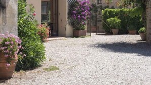 A courtyard with a gravel path, potted plants, and a building with a door and window. - Holiday Home in Pergine Valdarno With Pool (Pergine Valdarno)