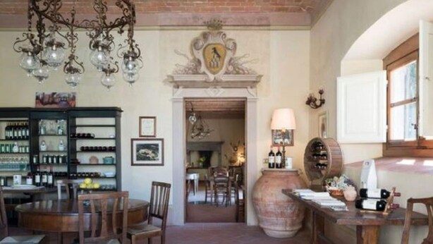 A dining area with a brick floor, wooden furniture, a chandelier, a wine rack, and a large vase. - Holiday Home in Pergine Valdarno With Pool (Pergine Valdarno)