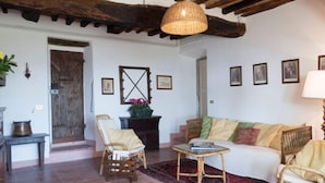 A cozy living room with a wooden ceiling, a wicker sofa, a small round table, and a wicker chair. - Holiday Home in Pergine Valdarno With Pool (Pergine Valdarno)