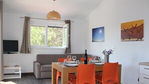A dining area with a table set for four, orange chairs, a bottle of wine, and a vase with flowers. - Apartment Near Sakarun Beach Dugi Otok (Sali)