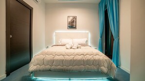 Un dormitorio con cama, lámpara de techo y ventana con cortinas.