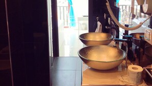 Un baño moderno con dos lavamanos grandes, un teléfono y un rollo de papel higiénico.