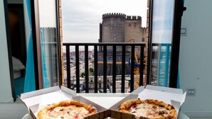 Dos cajas de pizza abiertas sobre una mesa, con vistas a un castillo a través de la barandilla de un balcón.