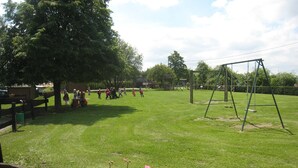 A grassy outdoor area with a swing set and a group of people playing. - Farmhouse in Aublain With Terrace (Couvin)