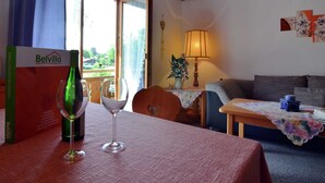 A cozy room with a wooden ceiling, a table with a glass and a bottle, a sofa, a lamp, and a window with a view of greenery. - Apartment in Bavaria by Soier See Lake (Bad Bayersoien)