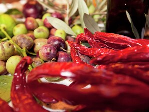 Diversas frutas, incluindo ameixas e maçãs verdes, com alguns pimentões vermelhos secos à vista.