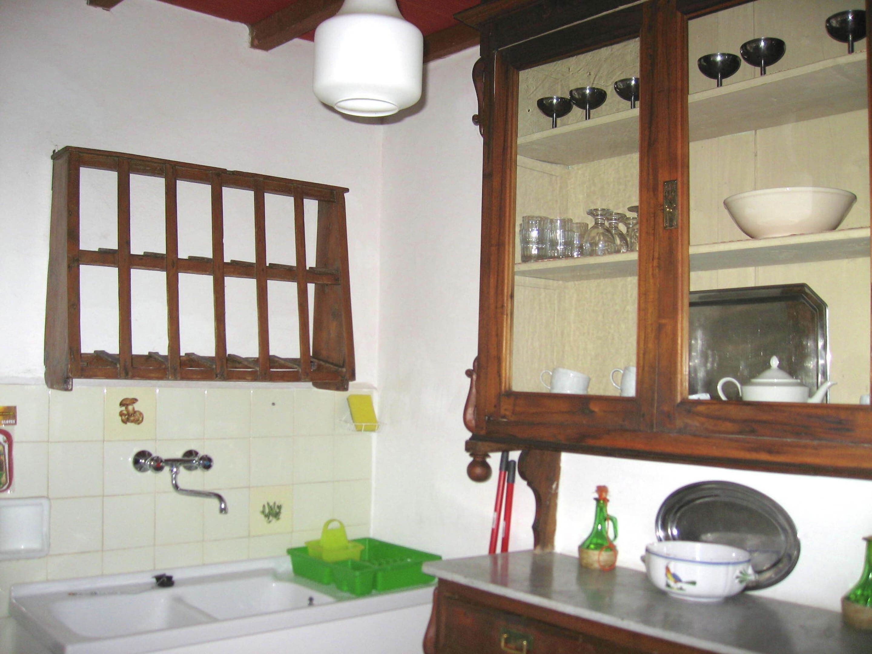 A bathroom with a bathtub, a green soap dish, a mirror, and a shelf with various items.