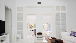 Ein modernes Wohnzimmer mit Fernseher, Couchtisch aus Holz und weißem Sofa.
