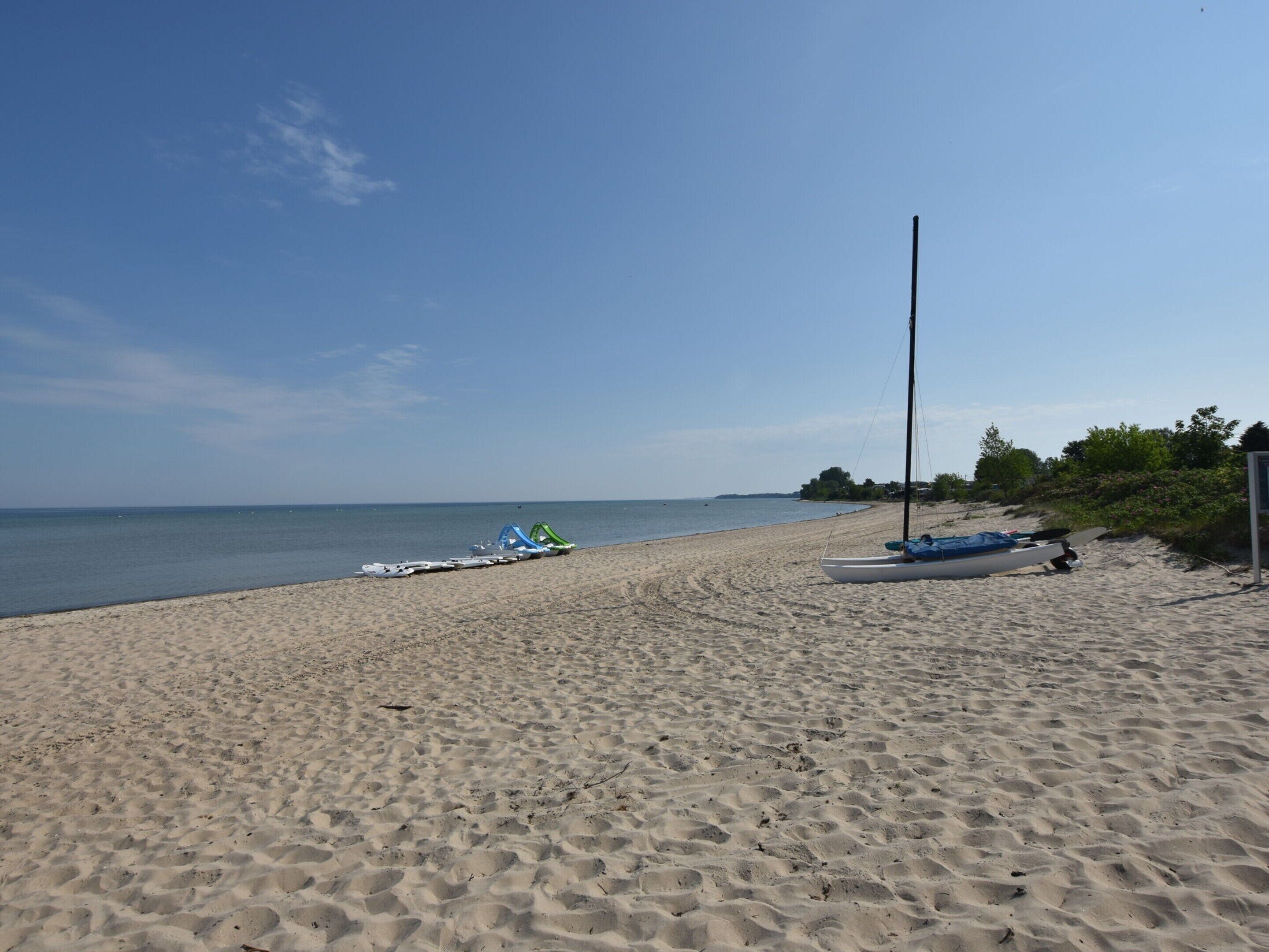 Una playa arenosa con barcos y un alto poste.