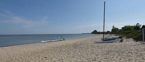 A sandy beach with boats and a tall pole.
