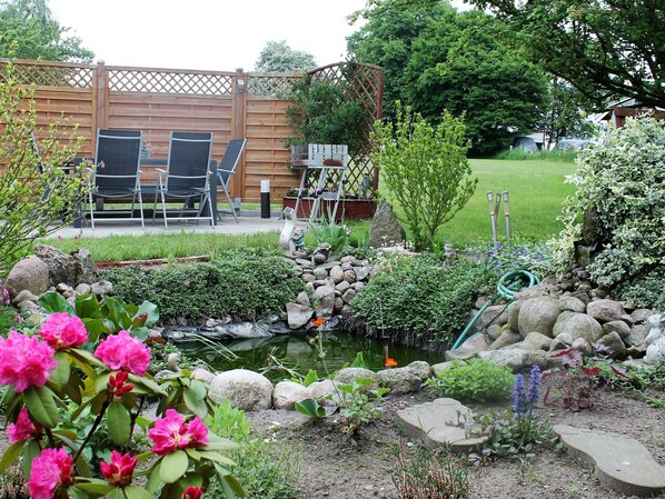 A garden with a pond, rocks, and flowering plants. - Lovely Apartment in Beckerwitz near Terrace (Hohenkirchen)
