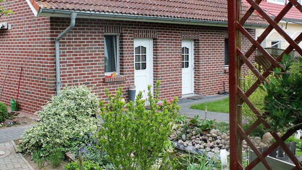 A brick house with a red-tiled roof, a white door, and a small window. - Lovely Apartment in Beckerwitz near Terrace (Hohenkirchen)